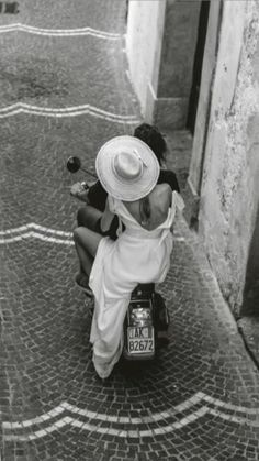 a woman sitting on the back of a scooter with a bird in her hand