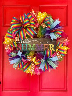 a colorful wreath with the words hello summer on it is hanging on a red door