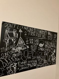 a blackboard with writing on it is hanging in a white walled room next to a wall