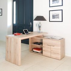 a desk with a lamp and pictures on the wall above it in a living room