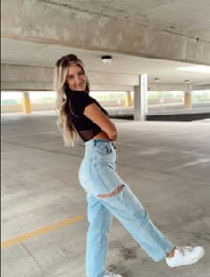 a woman standing in an empty parking garage with her legs spread out and smiling at the camera