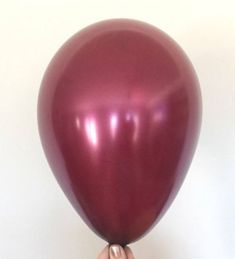 a person holding a large purple balloon in their right hand, with the other hand on top of it