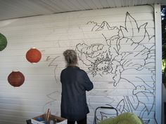 a woman standing in front of a white wall drawing on the side of a building