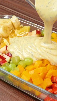 a tray filled with fruit and dressing being drizzled on top of it