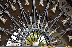 an ornate iron gate with flowers and leaves on the top, as seen from below