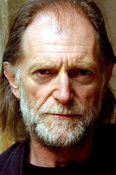 an older man with long hair and beard wearing a black shirt looking at the camera