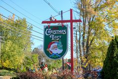 a sign for the christmas top with a santa clause on it's head hanging from a red pole