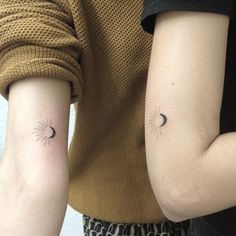 two people with matching tattoos on their arms, one is holding the other's arm