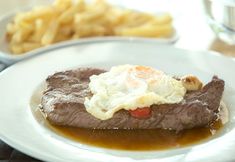 a plate with steak, mashed potatoes and gravy on it next to some french fries