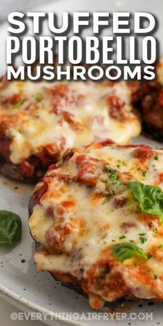 two stuffed mushrooms on a plate with cheese and basil sprinkled on top, text overlay says stuffed portobella mushrooms