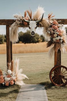 an outdoor ceremony with flowers, feathers and a cow skull