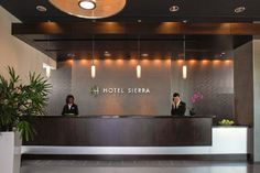 the front desk of a hotel with two people sitting at it's reception table