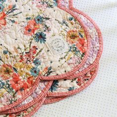 three quilted placemats with flowers and polka dots on white tableclothes