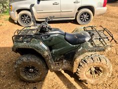 an atv is parked in the dirt next to a car and another vehicle behind it