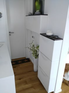 a vase with flowers on top of it next to a white cabinet in a room