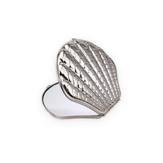 a silver seashell shaped brooch on a white background with clippings to the side