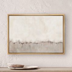 an abstract painting hangs on the wall above a wooden table with a plate and bowl