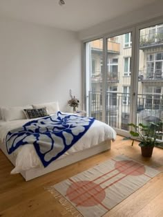 a bedroom with a bed, rug and large glass doors leading to an outside balcony