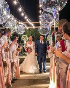 a bride and groom walking down the aisle with bubbles in front of them at night