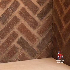 a cat sitting on the floor next to a brick wall