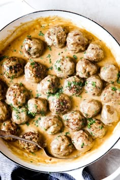 a pot filled with meatballs and gravy on top of a white table