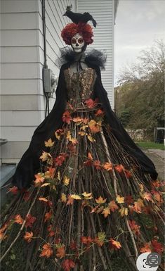 a woman in a dress made out of branches with leaves and flowers on the skirt