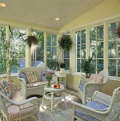 a sun room with wicker furniture and potted plants