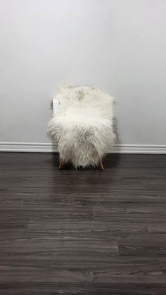 a white chair sitting on top of a hard wood floor next to a gray wall