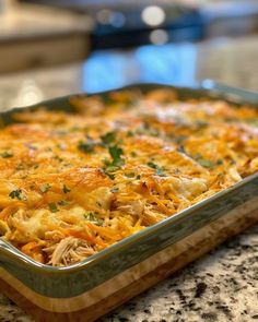 a casserole dish with chicken, cheese and parsley in it on a granite countertop