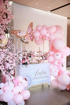 pink balloons and flowers are on display at the entrance to a wedding reception with a butterfly theme