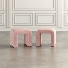 two pink stools in front of a white wall