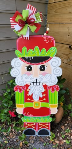 a wooden sign with a santa clause on it's face and a bow in his hat