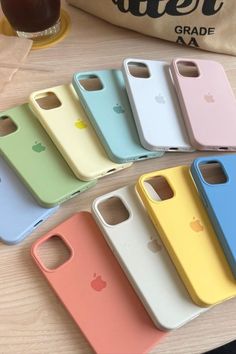 six different colored cases sitting next to each other on top of a wooden table in front of a bag