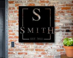 a brick wall with a sign on it that says smith est, and a potted plant next to it