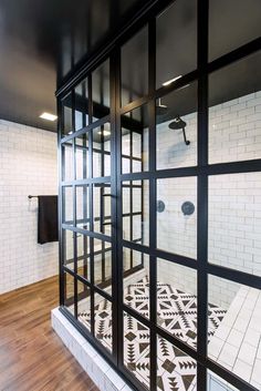 a bathroom with black and white tiles on the floor, glass doors to walk in shower