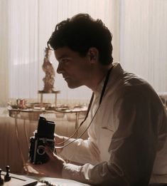 a man sitting at a table with a camera in his hand and looking into the distance