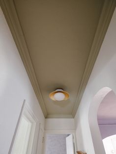 a hallway with white walls and a light fixture on the ceiling over the door way