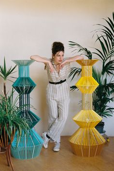 a woman standing in front of several colorful vases and planters on a table