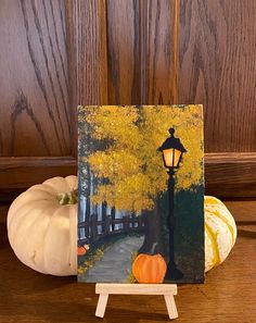 an easel with a painting of a street light and pumpkins in the background