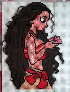 a cross stitch picture of a woman with long black hair holding a pink flower in her right hand