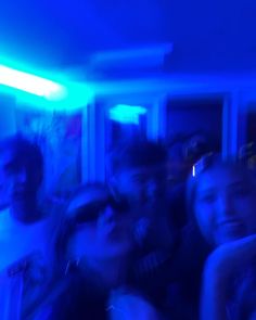 a group of people standing next to each other in a room with blue lights on the ceiling