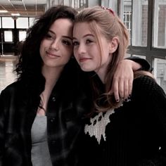 two young women are posing for a photo together in an office building, one is holding her arm around the other's shoulder