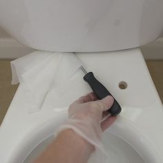 a person using a toilet brush to clean the bowl