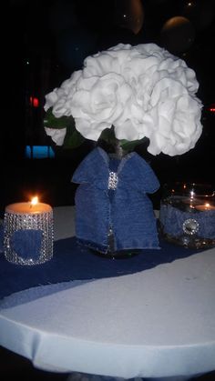 a white flower in a vase sitting on top of a table next to a candle