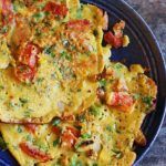 an omelet with tomatoes and other toppings on a blue plate