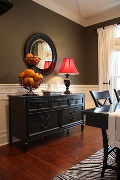 a dining room table with chairs and a mirror on the wall above it, along with a black dresser