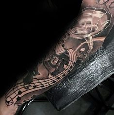 a man's arm with musical notes on it and an instrument in the middle