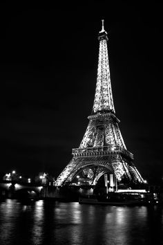 the eiffel tower lit up at night with lights reflecting off water in front of it