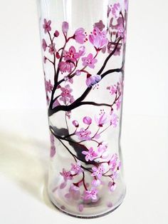 a glass vase with pink flowers painted on the outside and inside, sitting on a white surface