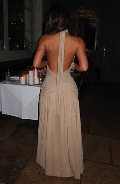 the back of a woman's dress at a dinner table with candles in it